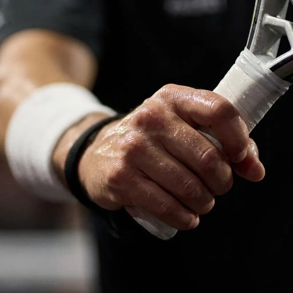 Padel player with a taped, sweaty grip on the racket handle